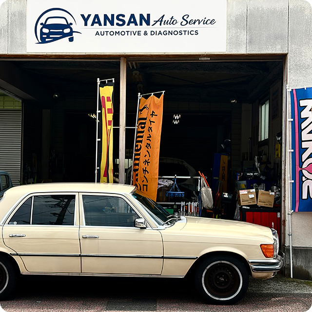 YANSAN Auto Serviceの看板と白い車が停まる店舗外観の写真